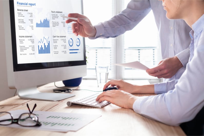 Two people studying financial report on computer screen