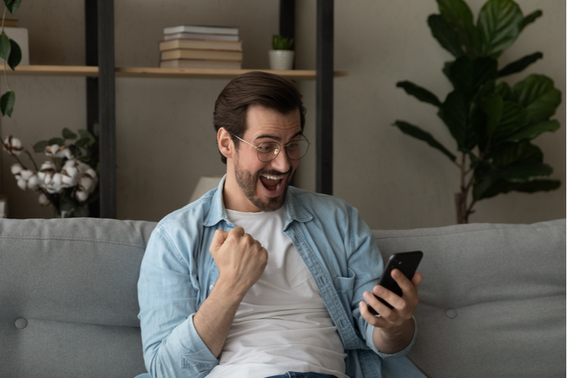 Man celebrating looking at phone